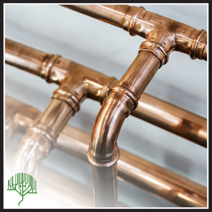 Close-up view of shiny copper plumbing pipes and fittings against a blue background, with a green tree logo in the lower left corner.